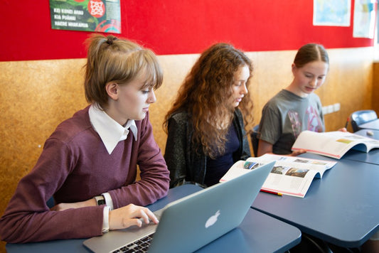 Three girls use LearnWell Digital on a laptop in a classroom, improving connection, collaboration and capturing attention.