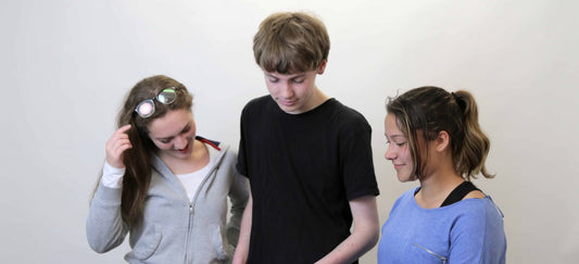 Three students stand around looking at a device depicting digital learning